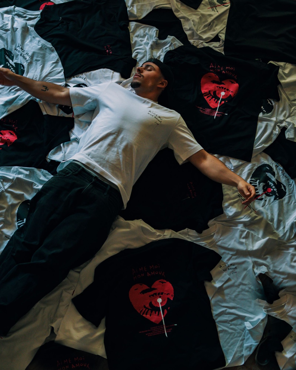 Vincent lying on the black and white T-shirts of the Aime-moi mon amour exhibition